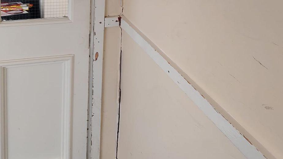 A crack on a wall next to an inside door.