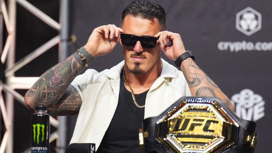 Tom Aspinall puts sunglasses on with the UFC belt in front of him