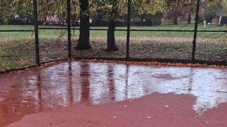 Water on the surface of a red-surfaced artificial playing area at Stockbrook Colts FC in Derby.