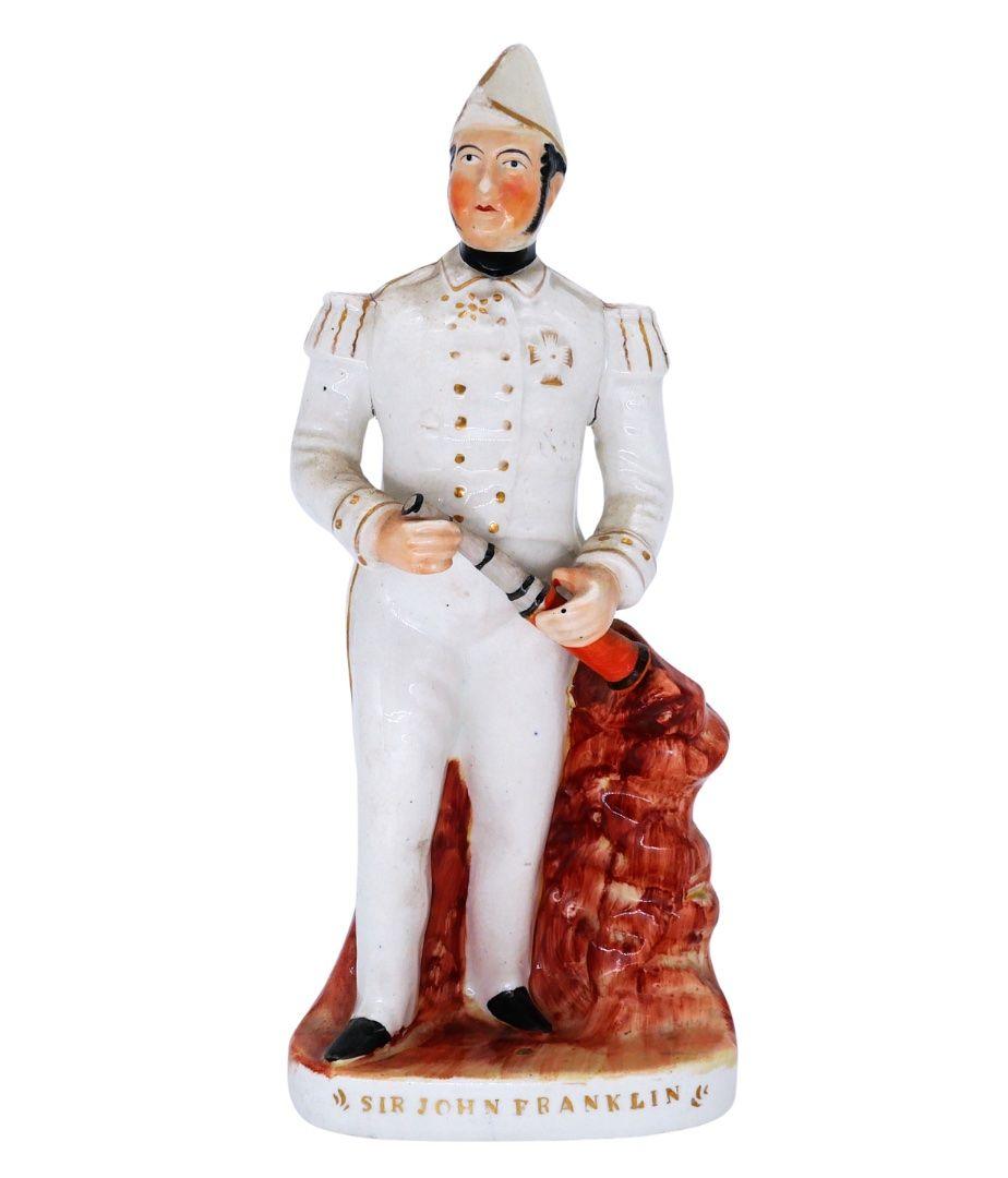 A ceramic figure of a man in a white naval suit with a telescope in his hands