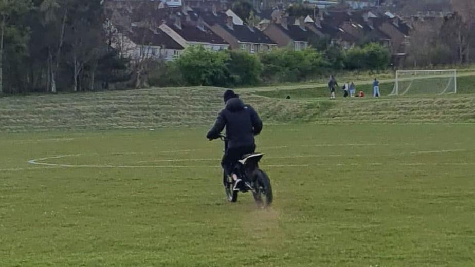 Someone riding a scrambler type bike on a football pitch