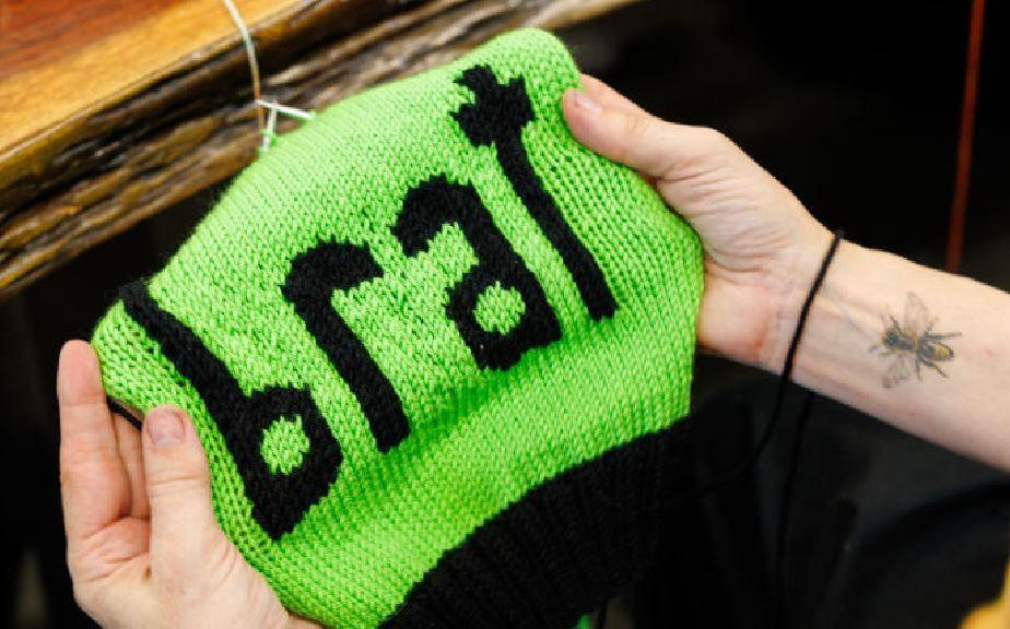 A green, knitted hat with the word brat on the front, made by Annette Corsino, owner of the Knitting Tree LA in California