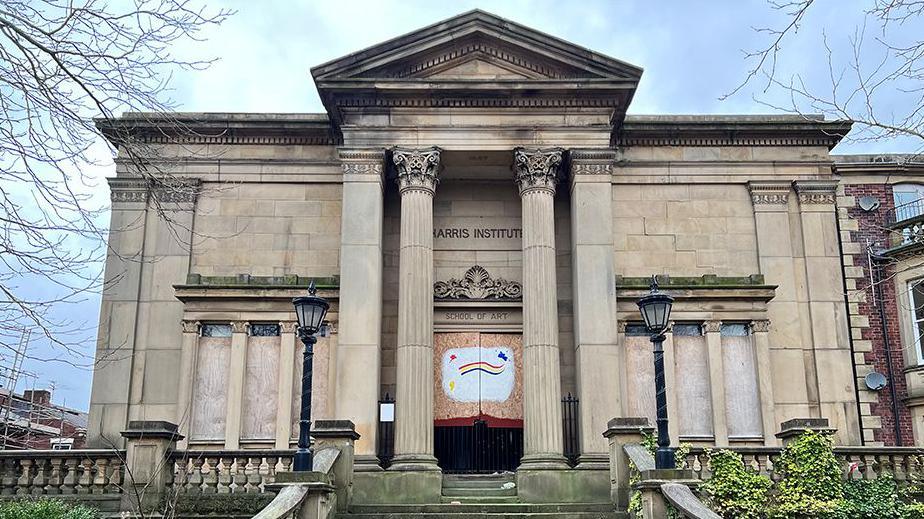 Grade I-listed Harris Institute, a large stone building with sweeping steps up to a grand pillared entrance and Victorian lamps either side. The ground floor windows are boarded up