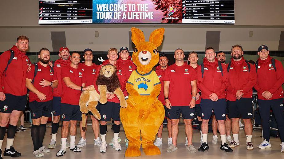 British and Irish Lions players pose after arriving in Australia., alongside a person in a kangaroo costume