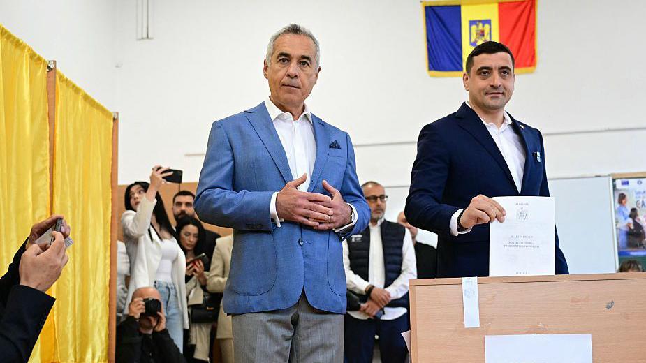Calin Georgescu looks on (L) as George Simion votes