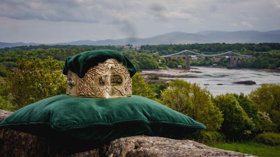 Coron Eisteddfod yr Urdd Ynys Môn gyda Phont Menai yn y cefndir