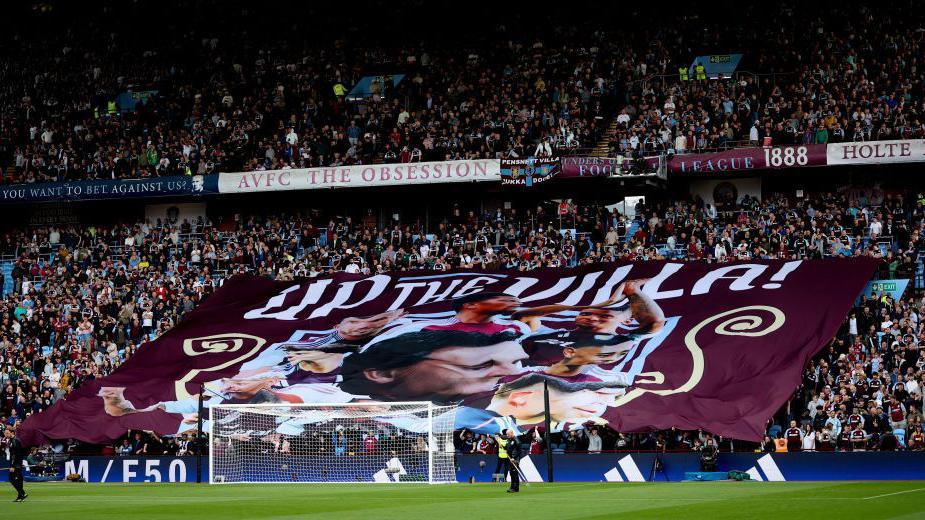 A banner saying 'Up the Villa' held up by fans during a Premier League match at Villa Park