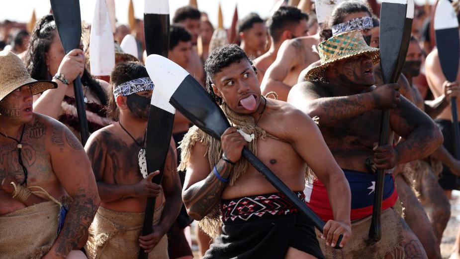 Māori Warriors perform a haka on the beach at Waitangi during a service to commemorate the national holiday