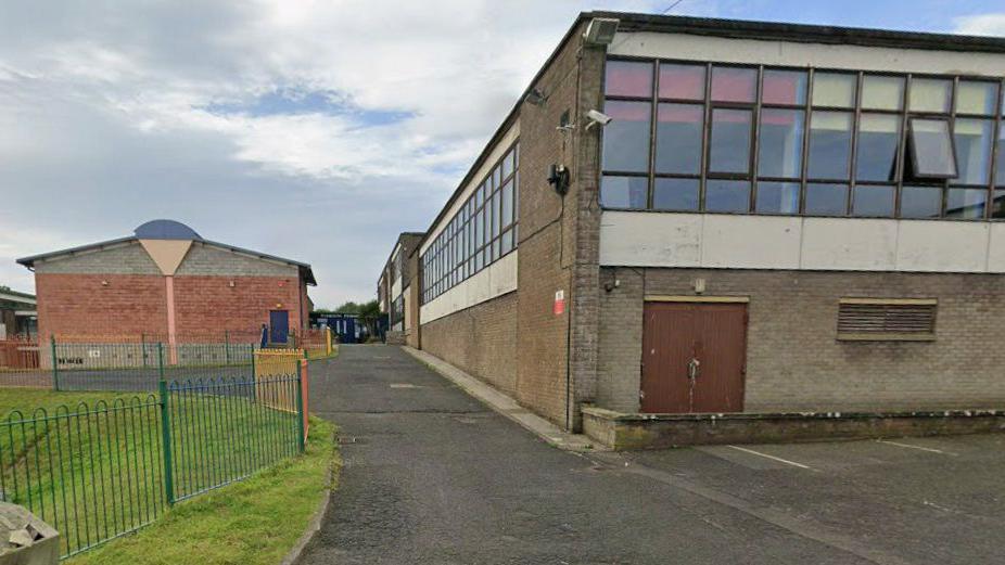 An old school building in the Borders with many windows and brick walls and tarmac around it