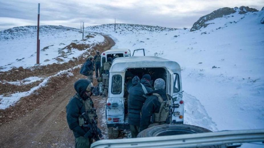 Troops stand in front of a vehicle on a snowy mountaintop - IDF via Reuters, 9 Dec 2024