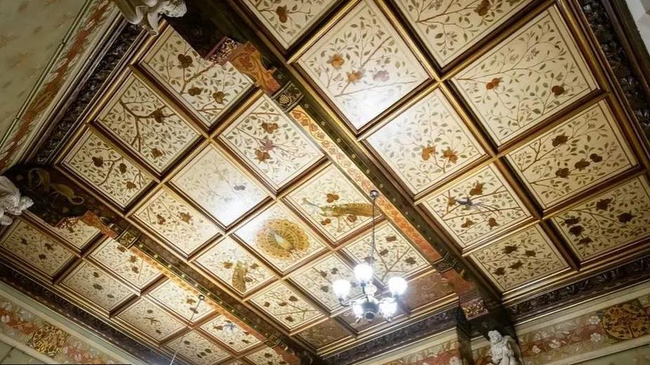 Ceiling squares of intricate, ornate designs, showing flowers and leaves on tree branches.