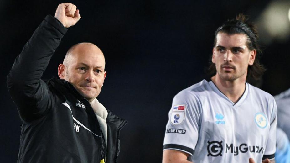 Alex Neil (left) and Tristan Crama (right) celebrate with Millwall's fans after their win at Portsmouth