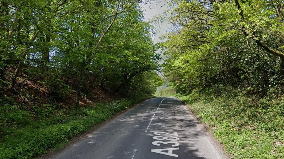 Google Street View image of the A382 in Chagford with no vehicles on the road and trees and grass verges either side