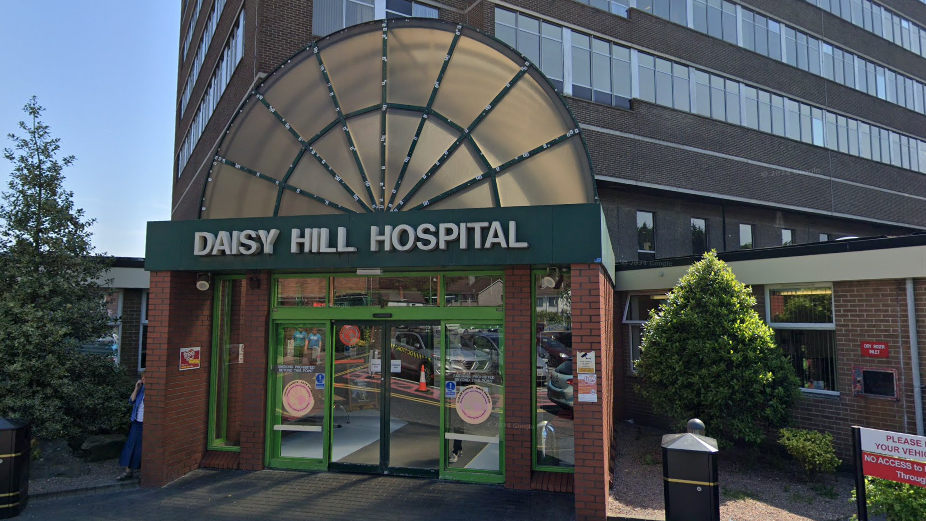 The entrance to a hospital. It says Daisy Hill Hospital in white over the doorway. There are sensor operated doors.