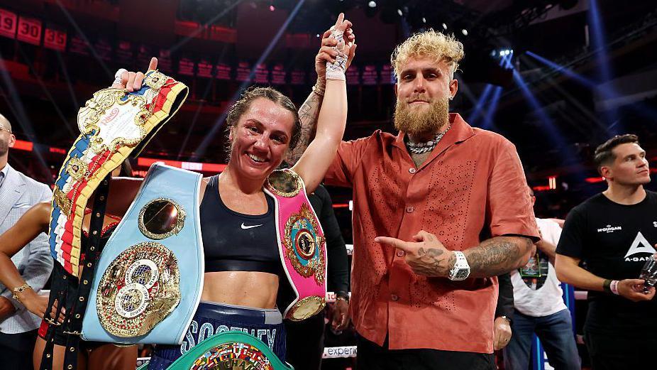 Ellie Scotney's hand is held up by Jake Paul 