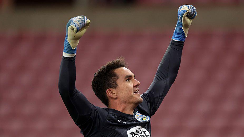 Huddersfield Town goalkeeper Lee Nicholls raises his arms in the air to celebrate with supporters after saving a Sunderland penalty in the Carabao Cup second round tie shoot-out.