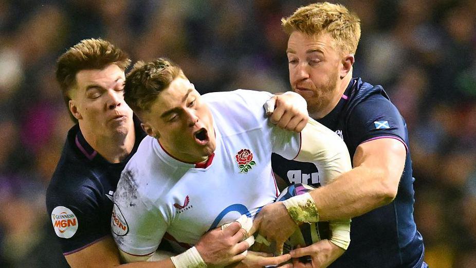 Scottish defenders Huw Jones and Kyle Steyn tackle England winger Tommy Freeman during the Six Nations game at Murrayfield on 14 February 2026