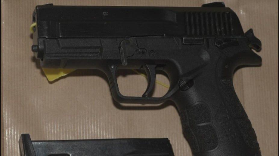 A black handgun lying on its side. A cartridge is at the bottom of the picture.