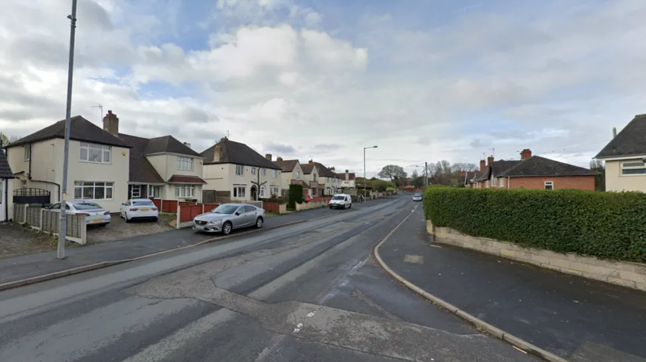 A view of a residential road from a street corner, with white semi-detached houses visible down the road