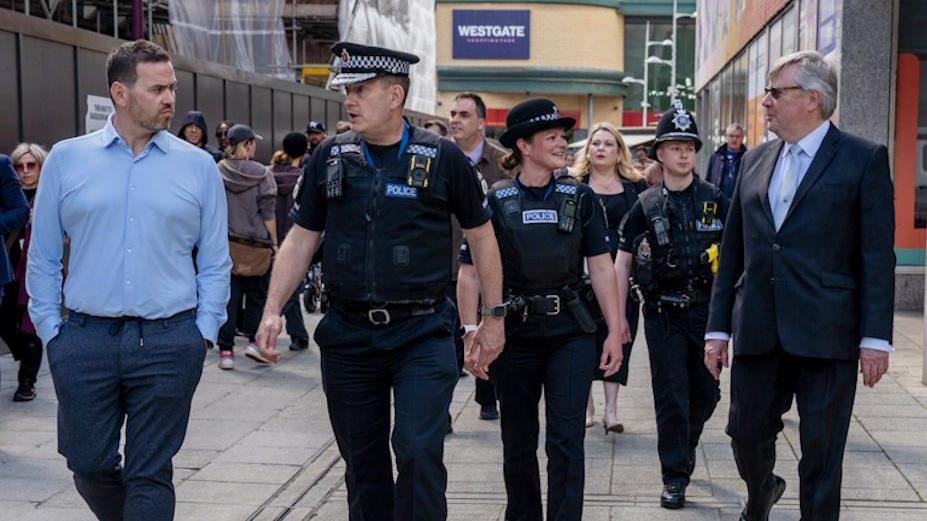 Ben-Julian Harrington walking with other police officers and people in a busy town centre street in Basildon.