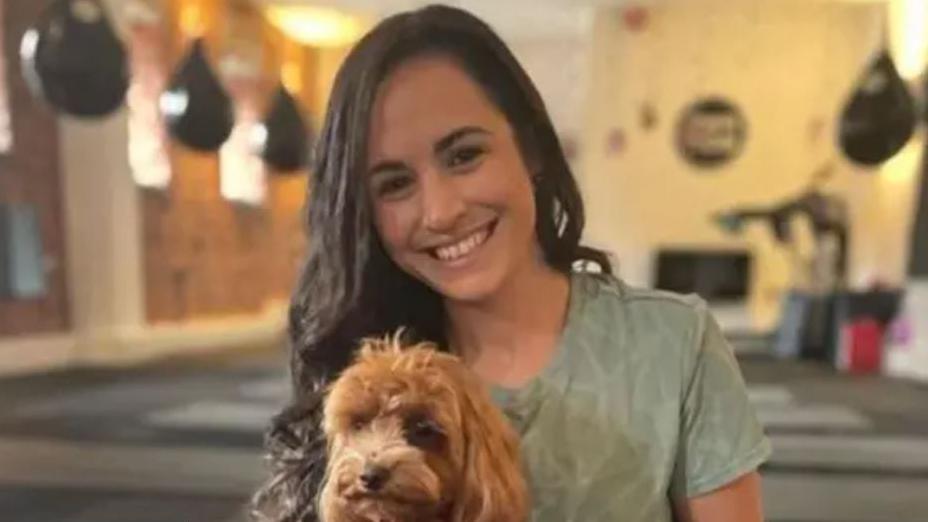 Teacher Leanne Lucas with long dark brown hair smiling holding her light brown dog 