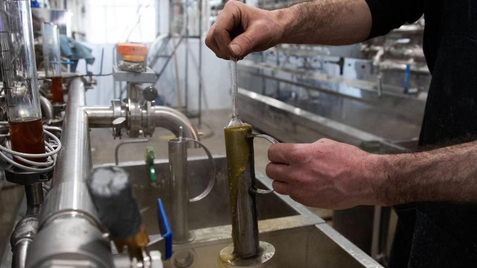 A worker measures the viscosity of freshly cooked maple syrup at a sugar shack near Lac Brome, Quebec, Canada.