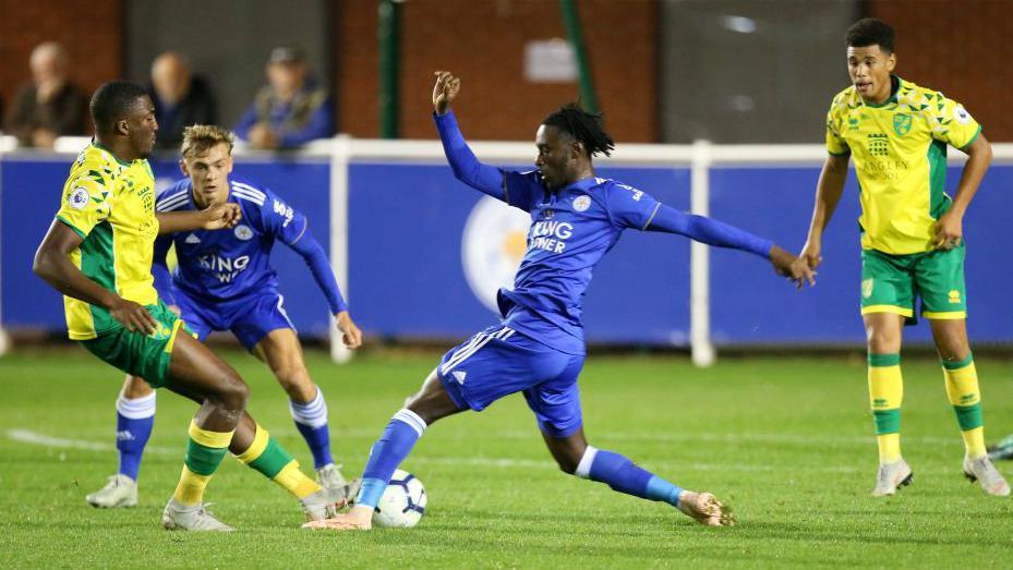 Devonte Aransibia wearing Norwich City kit is engaged in a tackle with Lamine Kaba Sherif of Leicester City