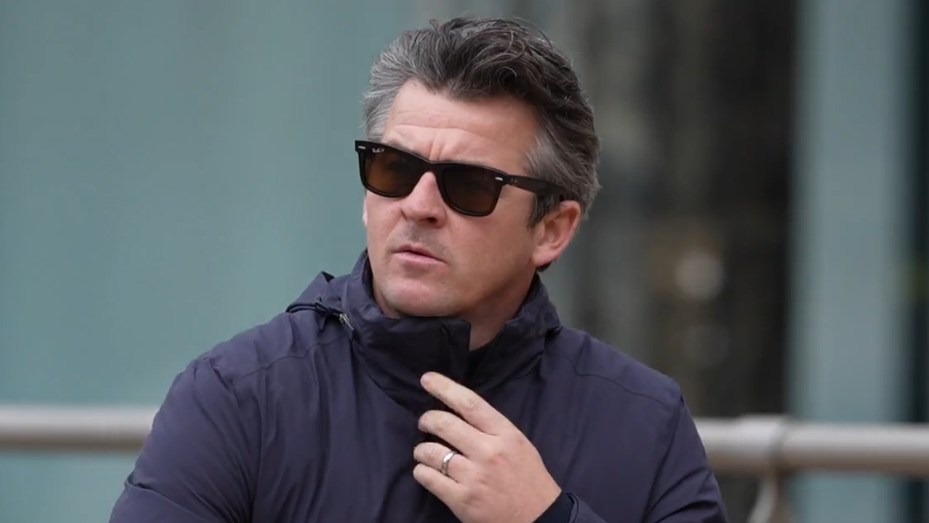 Joey Barton has dark greying hair and wears sunglasses. He is wearing a navy blue jacket