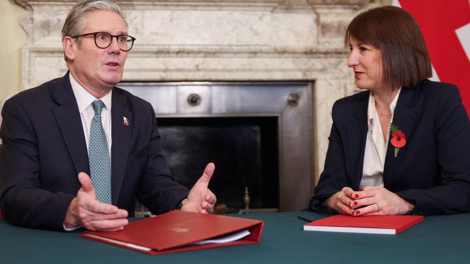 Rachel Reeves, chancellor, and PM, Sir Keir Starmer, sit at a desk talking 