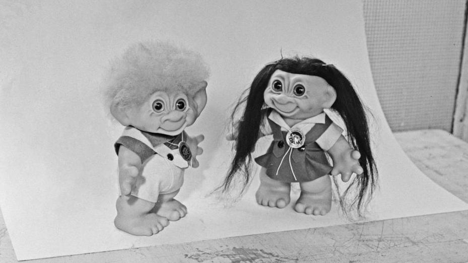 A black and white photo of two troll dolls