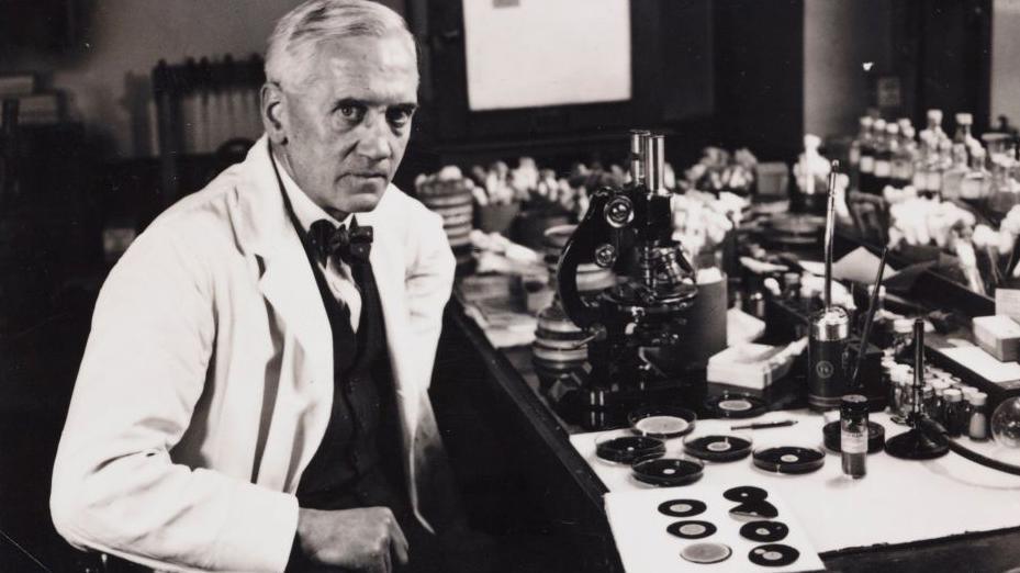 Sir Alexander Fleming sitting as his desk