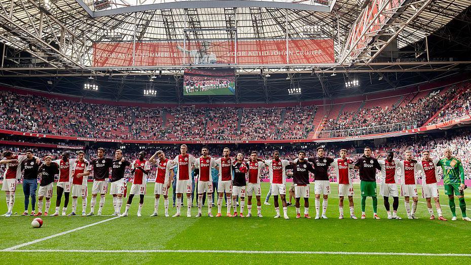 Ajax players stand in a line on the pitch at Johan Cruyff Arena