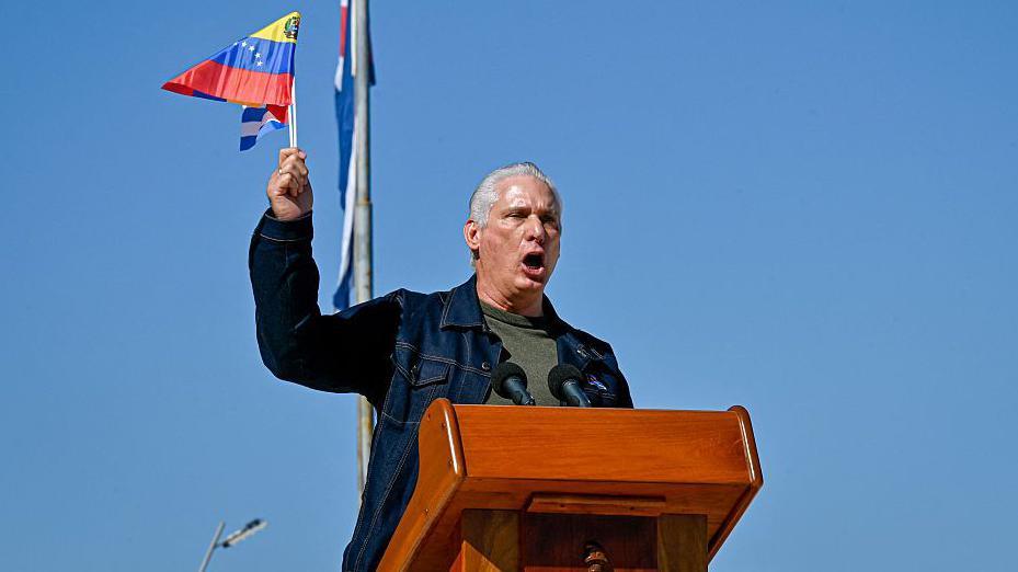 Cuba's President Miguel Diaz-Canel delivers a speech as he waves a Venezuelan national flag in support of Venezuelan leader Nicolas Maduro in Havana on 3 January 2026.
