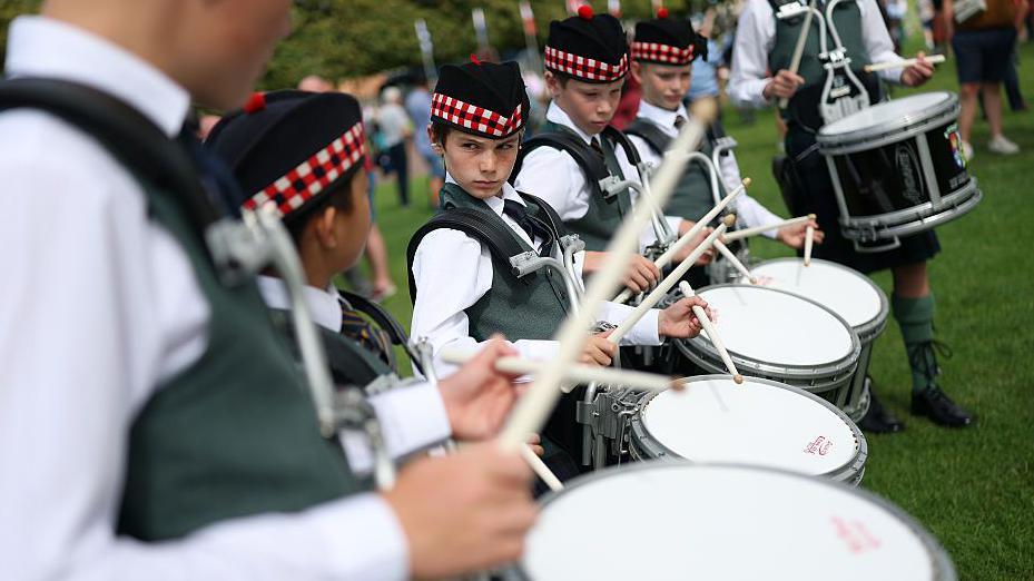 Young drummers standing in line . One of them has a stern look on his face.
