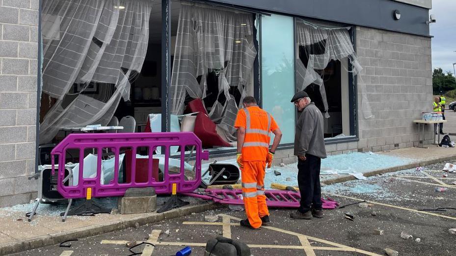 People clearing up the outside area of the Holiday Inn following the protests