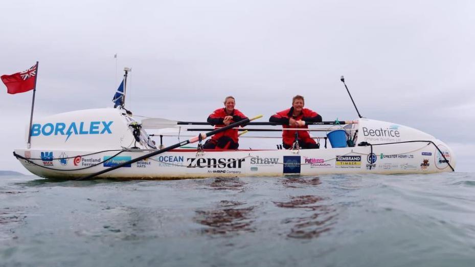 Rowers Mhairi Ross and Allan Lipp posing on their boat while at sea