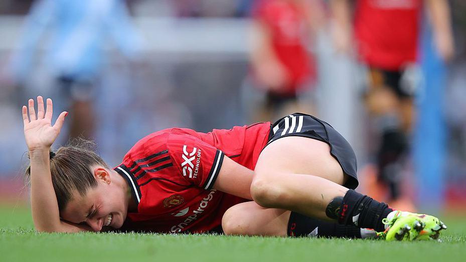 Ella Toone pide ayuda mientras está tumbada en el suelo.