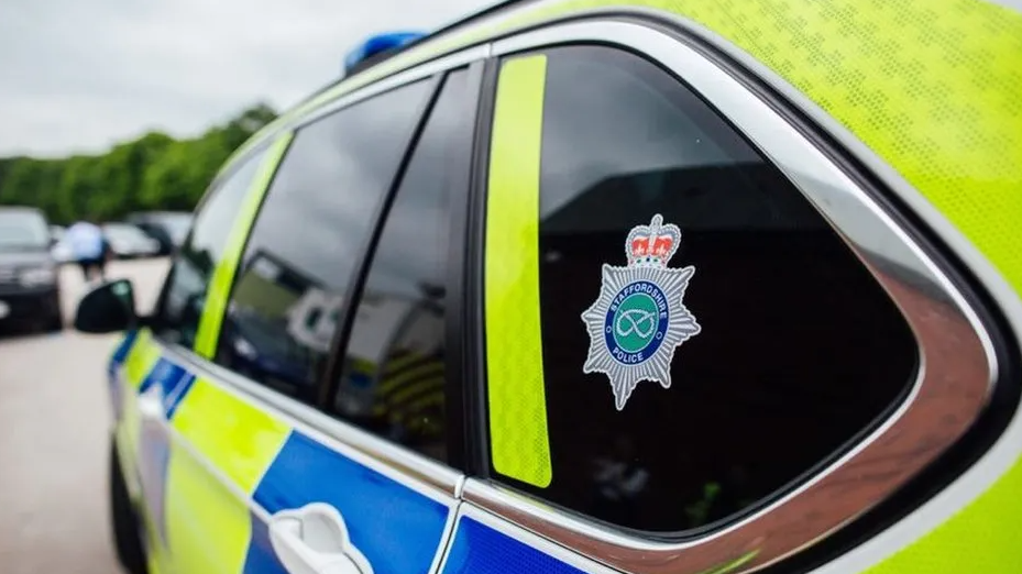 A Staffordshire Police car. It has hi-vis marking and a force logo. The side of the car can be seen only and the background is blurred. 