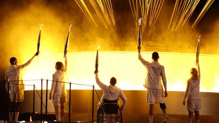 France's paralympic torchbearers, Charles-Antoine Kaoukou, Nantenin Keita, Fabien Lamirault, Alexis Hanquinquant and Elodie Lorandi hold the Paralympic flame in front of the Paralympic cauldron during the Paris 2024 Paralympic Games Opening Ceremony