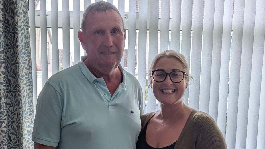 Kidney donor Stephen Topping, who is wearing a mint green polo shirt, and recipient Amy Smith, who has blonde hair and is wearing a brown cardigan. She also had black-rimmed glasses