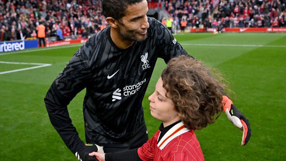 A young Liverpool fan shakes hands with David James at Anfield after the half-time penalty shoot out competition. 