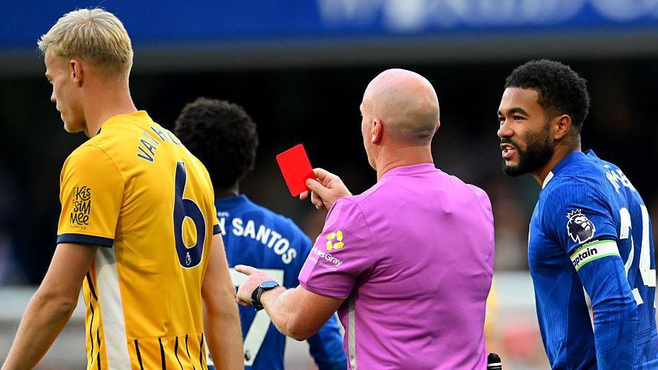 Simon Hooper shows red card to Chelsea player while Reece James speaks to him and Brighton's Jan Paul van Hecke walks by