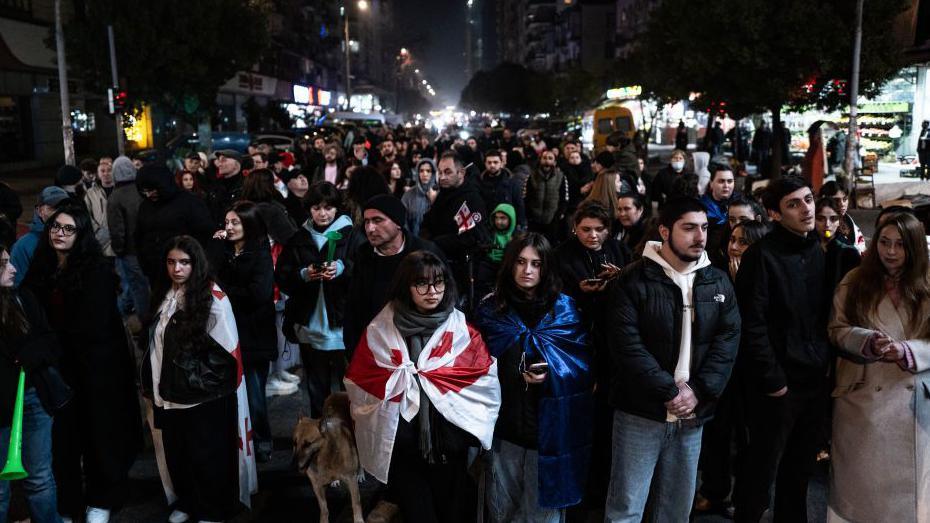 Protesters walk through Batumi in the dark, clad in Georgian flags