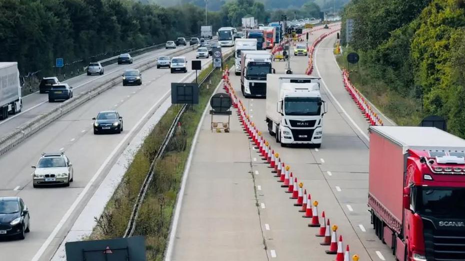 Lorries heading to Dover queuing on one side of the M20, herded by long rows of traffic cones