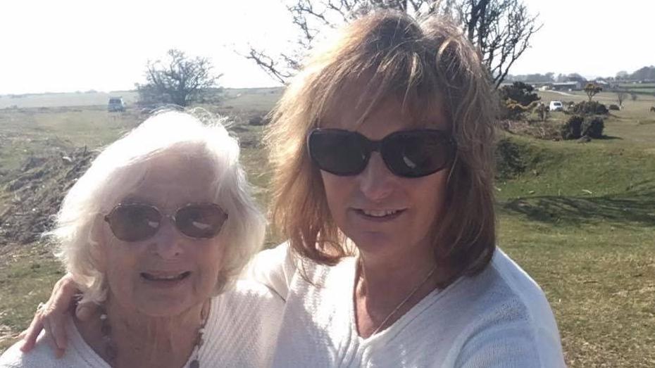 Alexis with her arm around her mother Fay, standing on moorland in the sunshine