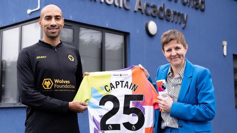 Ex-Wolves captain Karl Henry with Louisa Craig after surprising her with the award. They are standing outside the school and holding a special shirt.