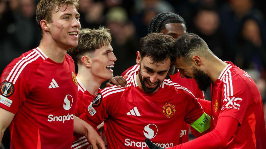 A smiling Bruno Fernandes celebrating his third goal with his happy teammates.