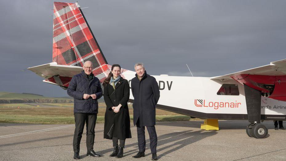 First Minister John Swinney, council leader Heather Woodbridge and chief executive Oliver Reid in front of a plane.