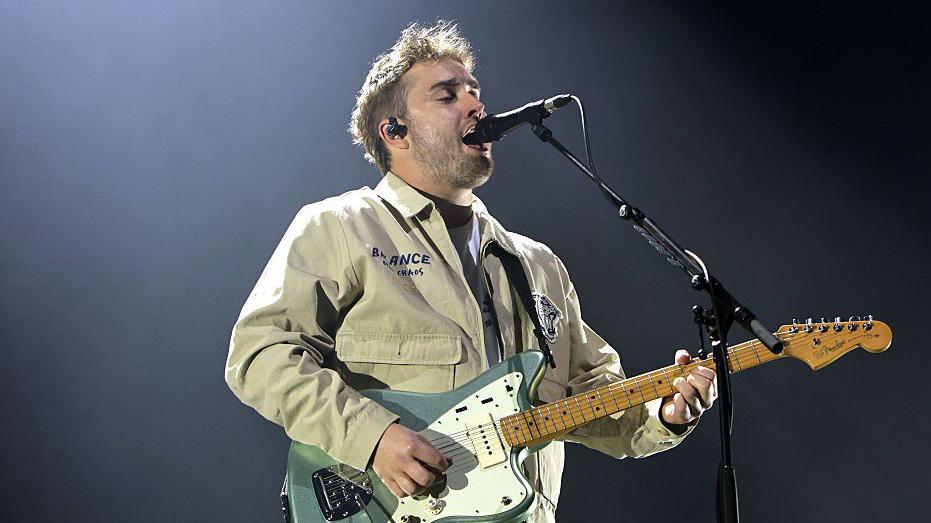 Sam Fender performing on stage.