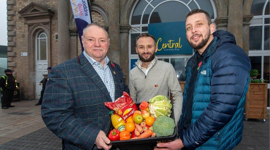 Three men hold a box of food outside the Queen's Building in Wolverhampton